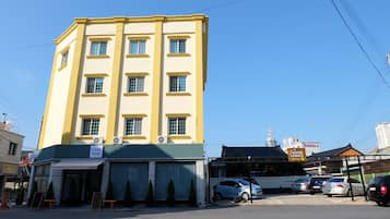 Ein mehrstöckiges Gebäude mit einem Café namens "Cafe Mar" im Erdgeschoss, einem Parkplatz mit mehreren Autos und einem Schild für "Hostel Lespace" im Hintergrund.