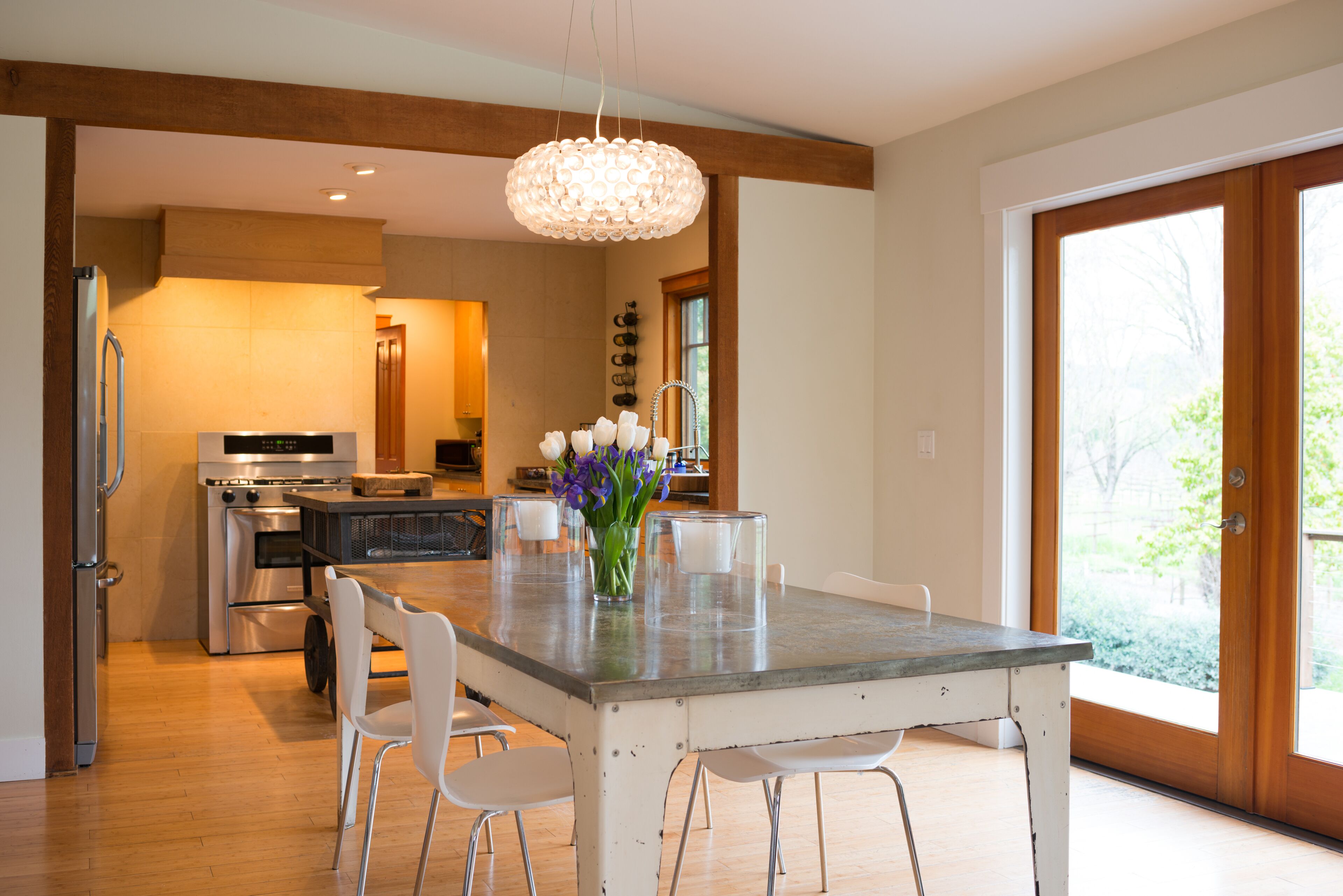 A modern kitchen with stainless steel appliances, a central island with chairs, and a large window providing natural light.
