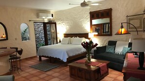 Une chambre bien éclairée, comprenant un lit, un canapé, une table basse et un coin repas.