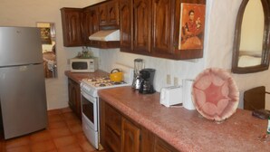 Une cuisine avec des meubles de rangement en bois, une cuisinière à gaz, un four à micro-ondes, un réfrigérateur et un évier.
