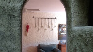 Une pièce avec un mur en pierre rustique, un luminaire suspendu, une chaise et une petite table.
