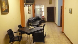 Un área de comedor con una mesa y sillas, un sofá y un televisor instalado en la pared.