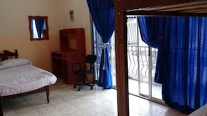 Un dormitorio con una cama, un escritorio y una silla. Hay una ventana con cortinas azules.