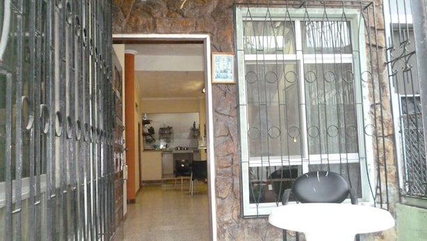Un pasillo estrecho con una verja de metal, un muro de piedra y una ventana con barrotes.