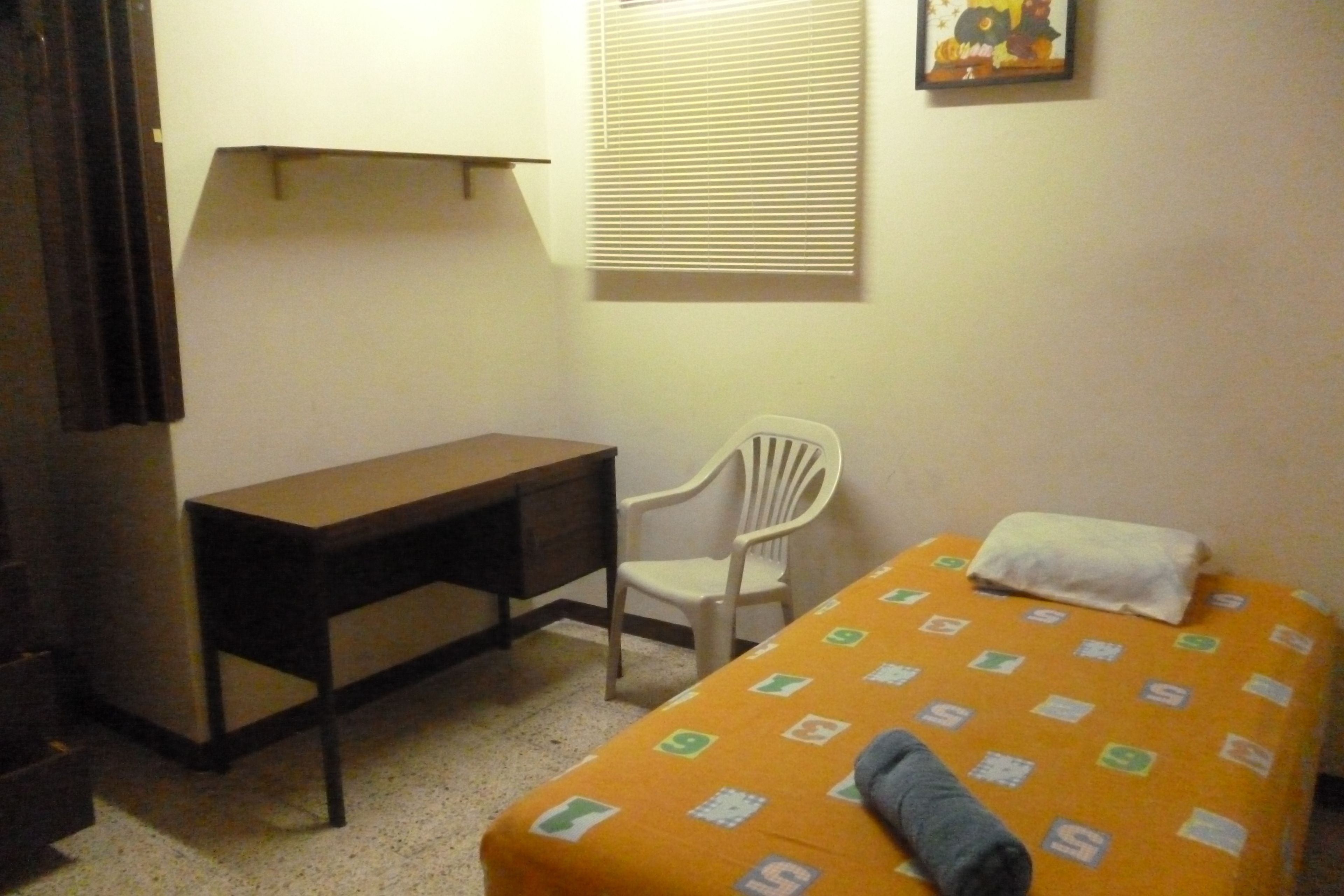 A small room with a bed, a desk, and a chair.