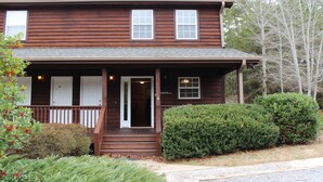 A two-story wooden house with a front porch, a door, and a small window. - Magic Moments - Pet Friendly Townhome in Innsbruck Golf Community (Helen)