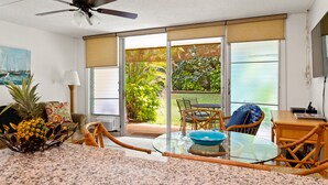 Une cuisine dotée d’un plan de travail en granit, d’une table à manger avec des chaises, d’un ventilateur de plafond et d’une vue sur un jardin, visible à travers de grandes portes-fenêtres coulissantes.