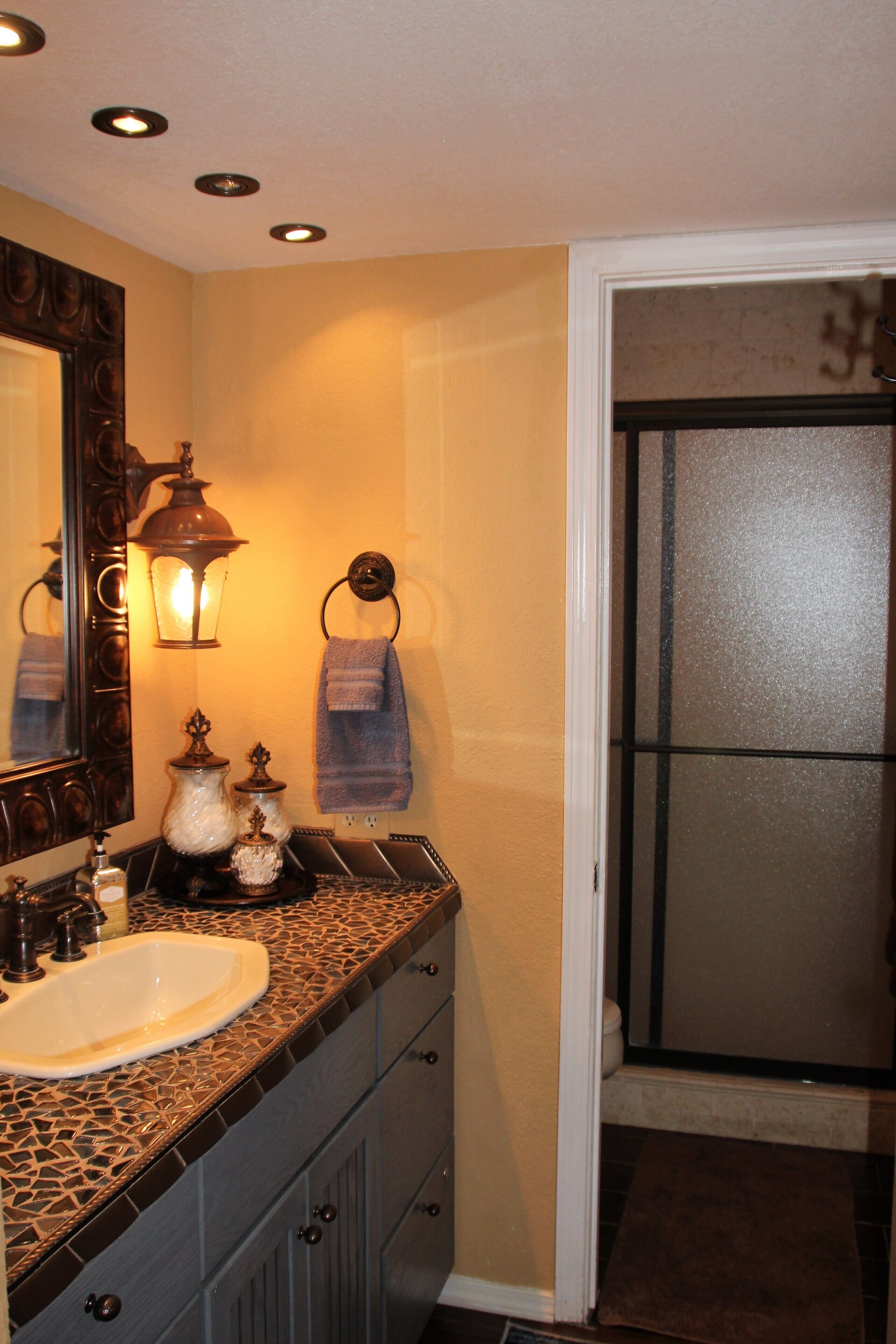 A bathroom with a sink, vanity, mirror, and a towel rack.