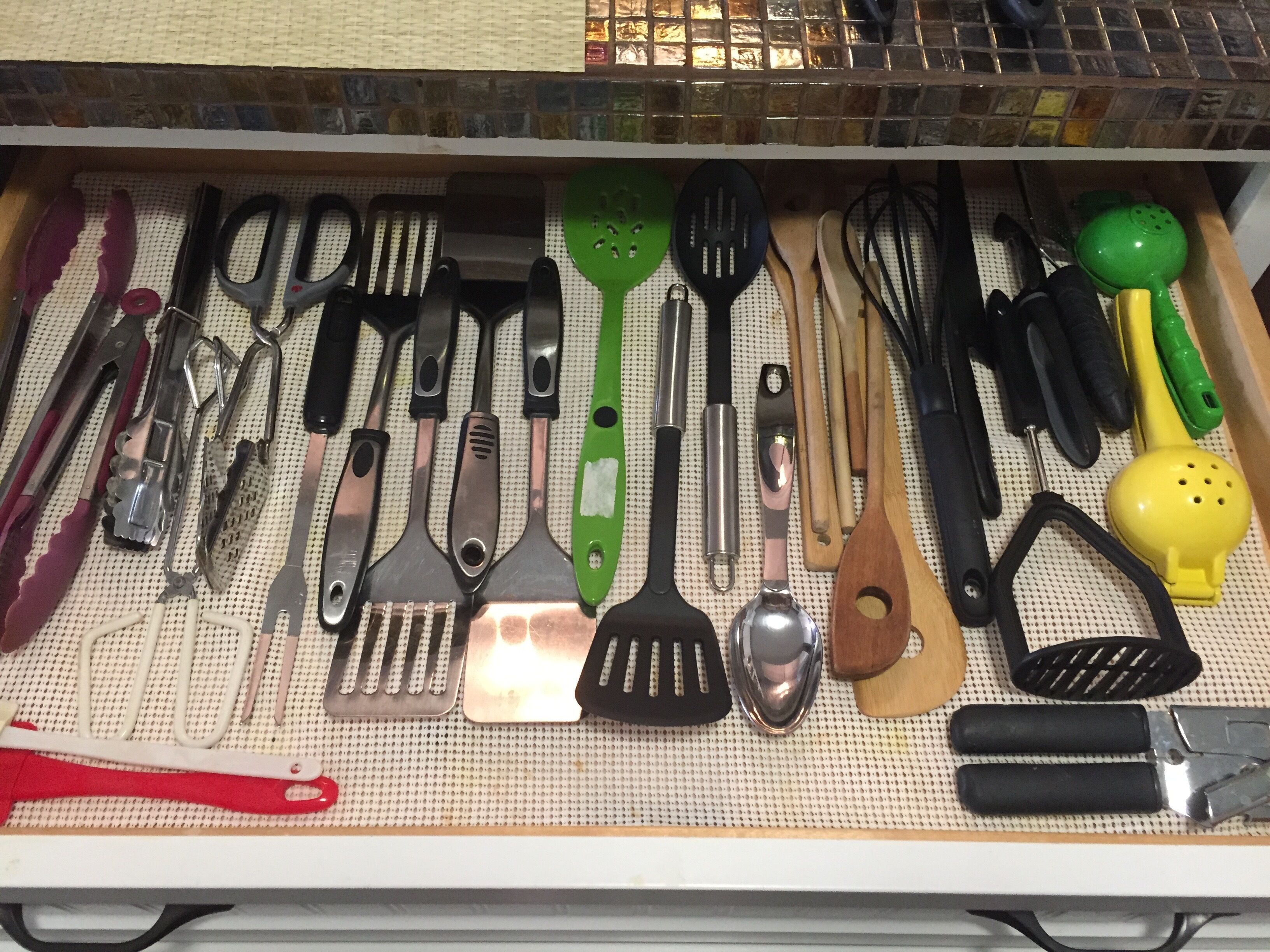 A drawer with various kitchen utensils neatly organized on a pegboard.