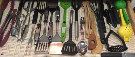 A drawer with various kitchen utensils neatly organized on a pegboard.