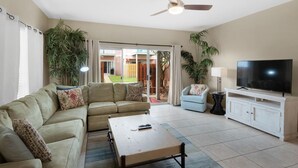 A living room with a sofa, a coffee table, a TV, and a ceiling fan. - ⭐Amazing Location-Complex Pool-Balcony and Patio-Corner Unit-2BR Gulf Walk 606⭐ (Destin)