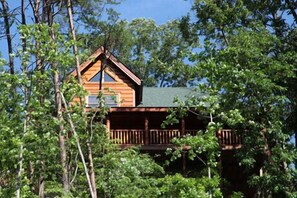 Escape to a secluded cabin surrounded by forested tranquility, with a balcony offering a peaceful retreat.