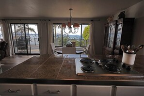 A kitchen with a central island, a dining area with a view, and a large window.