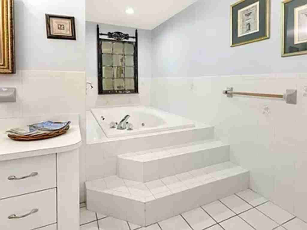 A modern bathroom with a large bathtub, a vanity with drawers, and framed pictures on the wall.