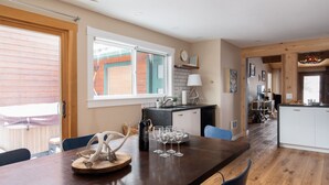 Una cucina moderna con un tavolo da pranzo in legno, forno integrato e vista sul giardino.