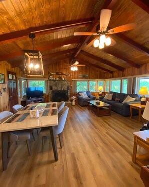 A spacious living area with a wooden ceiling, a fireplace, a dining table with chairs, and a sofa set. - Relax in our cozy Black Mountain Cottage, near Blue Ridge Parkway (Black Mountain)
