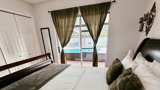A hotel room with a bed, a view of an outdoor pool, and a door to the left. - Affordable 3 Bedroom Home W / Private Pool. Minutes from Orlando's theme parks (Orlando)