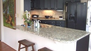 A kitchen with dark cabinets, a granite countertop, a sink, and a refrigerator. - Spacious,Friendly,Warm and Cozy 5 Bedroom 3 Bath Family Home (Banner Elk)