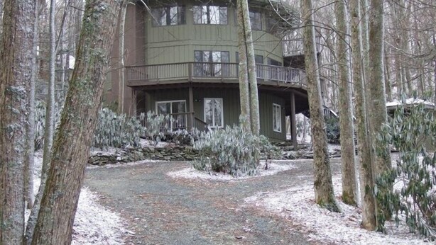 A two-story house with a balcony, surrounded by trees and a gravel path. - Spacious,Friendly,Warm and Cozy 5 Bedroom 3 Bath Family Home (Banner Elk)