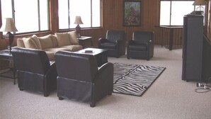 A living room with a sofa, two armchairs, a coffee table, a zebra-patterned rug, and a television. - Spacious,Friendly,Warm and Cozy 5 Bedroom 3 Bath Family Home (Banner Elk)