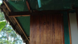 A wooden door with the number 07, a thatched roof, and a wooden staircase leading up to it. - Paradise Amazon Lodge & Adventure (Tambopata)