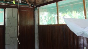 A room with a thatched roof, wooden walls, a large window, and a hanging light fixture. - Paradise Amazon Lodge & Adventure (Tambopata)
