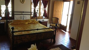 Una habitación con cama, una silla, un armario de madera y un espejo.
