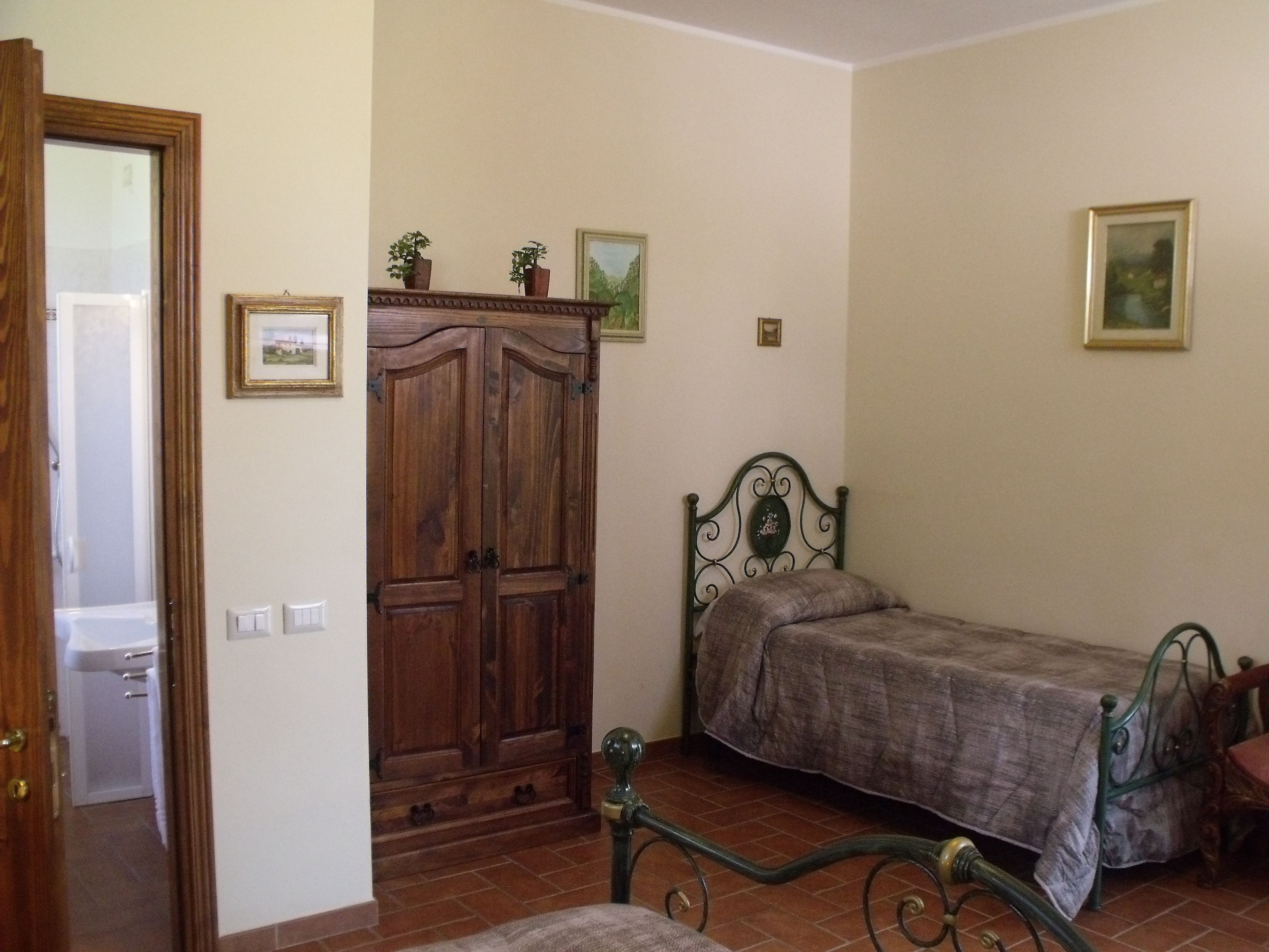 Un dormitorio con un armario de madera, una estructura de cama de metal y una mesita.