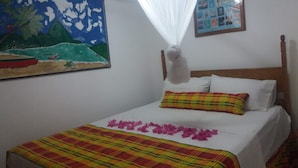 A bed with a plaid bedspread, a white pillow, and a colorful pillow.