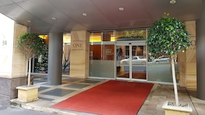 A hotel entrance with a red carpet, glass doors, and two potted plants. - Executive apartment waterfront Darling Harbor ICC Sydney  (Sydney)