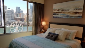 A hotel room with a large bed, a city view, a painting on the wall, and a window with curtains. - Executive apartment waterfront Darling Harbor ICC Sydney  (Sydney)