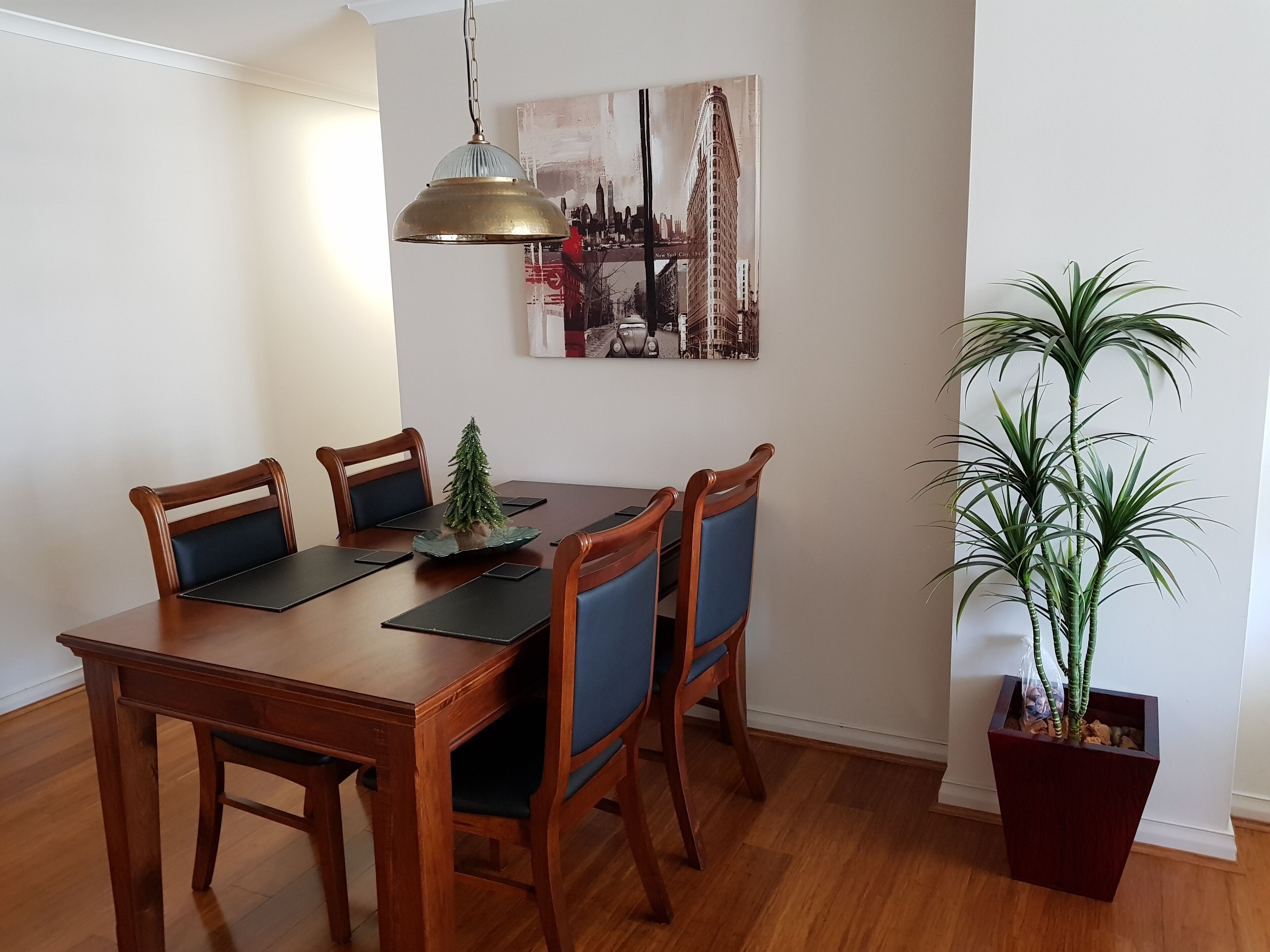 Un coin repas avec une table en bois, quatre chaises, un petit sapin de Noël et une plante en pot.