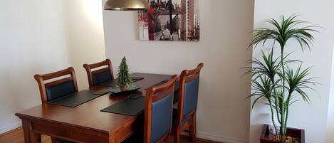 Un coin repas avec une table en bois, quatre chaises, un petit sapin de Noël et une plante en pot.