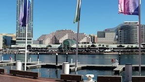 A waterfront marina with docked boats, a marina building, and a city skyline in the background. - Executive apartment waterfront Darling Harbor ICC Sydney  (Sydney)