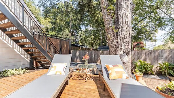 Une terrasse avec deux chaises longues, une petite table et un escalier en bois.