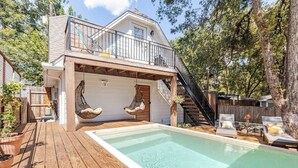 Une maison à deux étages avec une terrasse en bois et une piscine.