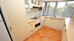 A kitchen with white cabinets, a microwave, a toaster, and a sink. - Stunning Penthouse in the Heart of Town – Views, WiFi & Walk to Everything (South West Rocks)