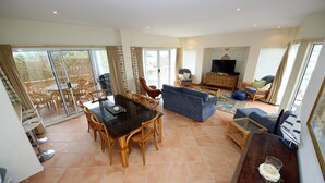 A spacious living area with a dining table, sofas, and a TV. - Stunning Penthouse in the Heart of Town – Views, WiFi & Walk to Everything (South West Rocks)