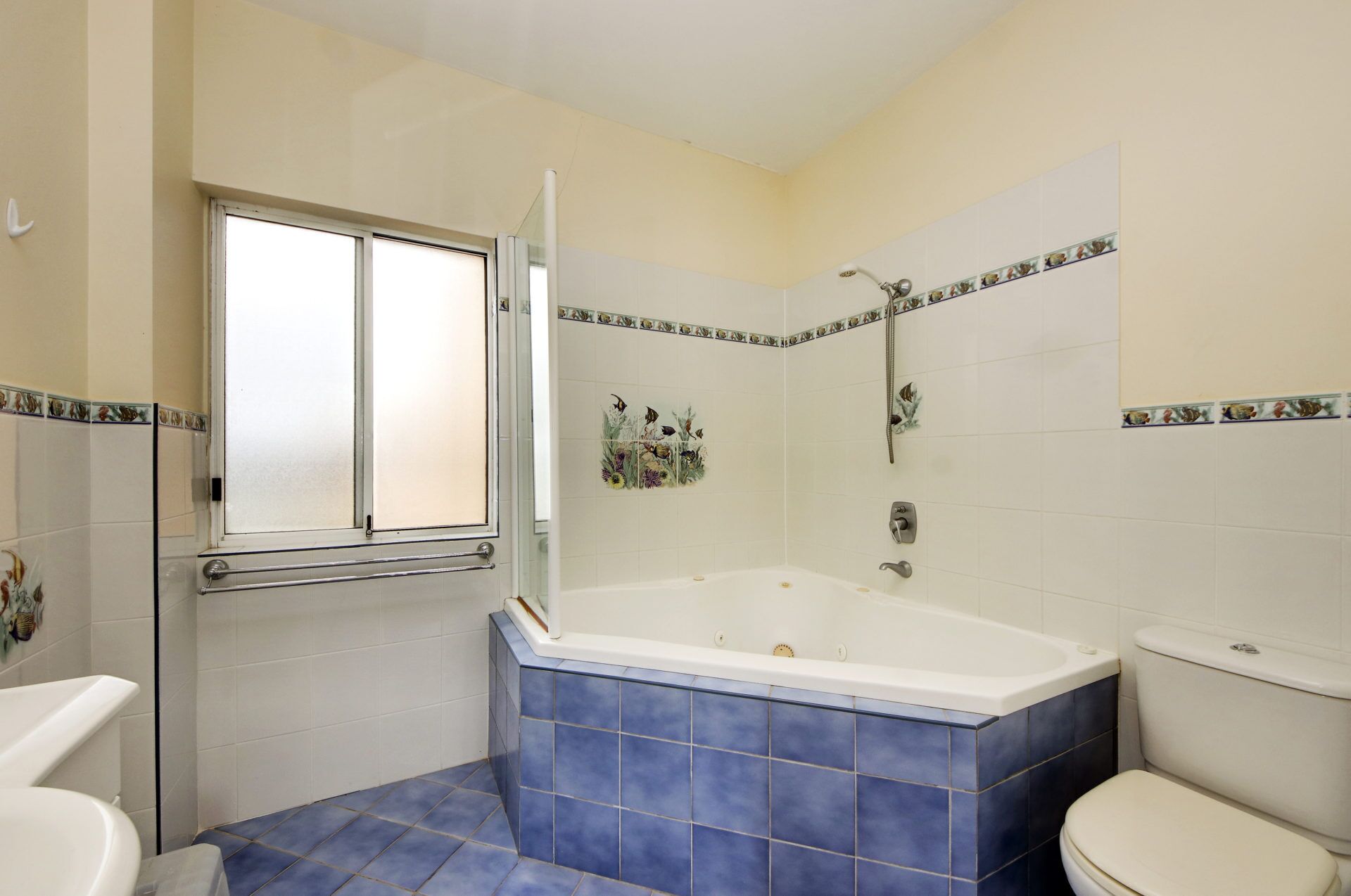 Un baño con bañera, inodoro y ventana.
