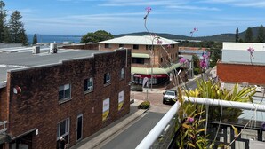 A street view with buildings, a clear sky, and a distant view of the sea. - Stunning Penthouse in the Heart of Town – Views, WiFi & Walk to Everything (South West Rocks)