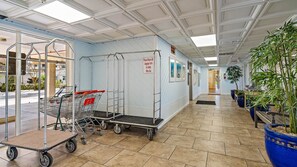 Un espace intérieur propre et bien éclairé, doté d’un sol carrelé, de chariots de courses en métal et d’un panneau indiquant qu’il faut rapporter tous les chariots à bagages.