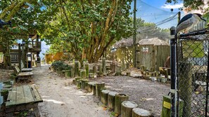 Une structure en bois, dotée de bancs et d’une clôture, entourée d’arbres et s’ouvrant sur un ciel dégagé.