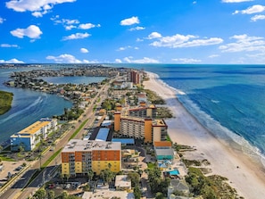 Un hotel costero con varias edificaciones, una playa y un puerto deportivo.