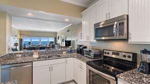 A modern kitchen with granite countertops, stainless steel appliances, and a view to the outside.