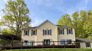A two-story house with a gabled roof, a front porch, and a covered deck area.