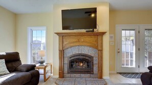 A living room with a fireplace, a television mounted above it, and two sofas.