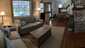 A spacious living room with a grey sofa, a wooden coffee table, and a stone fireplace. - Relax and get away! Beautiful beach house, close to OGT Village and Beach  (Ogunquit)