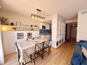 A compact living space with a dining area, kitchenette, and a seating area with a sofa.
