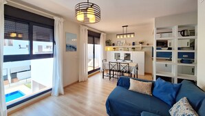 A modern living room with a blue sofa, a dining area with a table and chairs, and a kitchen with white cabinets and shelves. - Al 318 - Penthouse with terrace  near the beach (Vera playa)