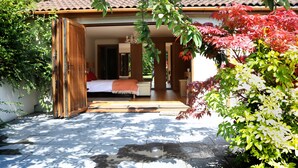 Ein traditioneller japanischer Raum mit Tatami-Böden, einem niedrigen Holzbett und einer Schiebetür zu einem Badezimmer.